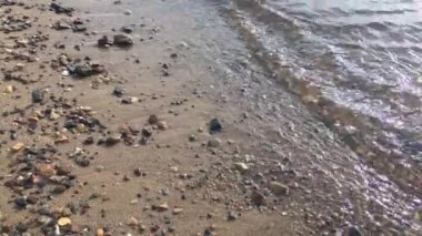 Nehir veya denizin kumsalında. Şeffaf su yüzeyi. Yaz doğası arka planı, kapat