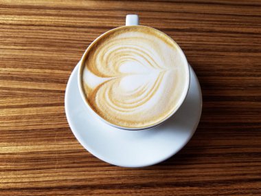 Kahveli kahve fincanı ve ahşap masa üzerinde kahve sanatı..