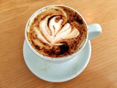 Cappuccino Kahve fincanının en iyi manzarası, üzerinde köpük ve kakao olan tahta masa..