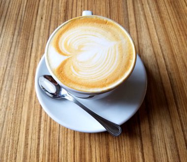 Cappuccino Kahve fincanının en üst manzarası. Kırsal ahşap bir masada köpüklü sanat eserleri..