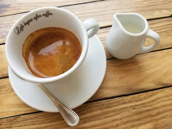 Espresso Kahve ve süt beyaz bardaklar ahşap bir kırsal masada.