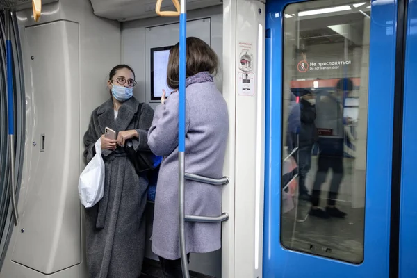 Moskova. - Rusya. 19 Ekim 2020. Metro vagonunda genç bir kadın. Yolcunun yüzünde koruyucu bir tıbbi maske var. Viral enfeksiyon önleme önlemleri. Toplu taşımacılıkta sosyal uzaklık.