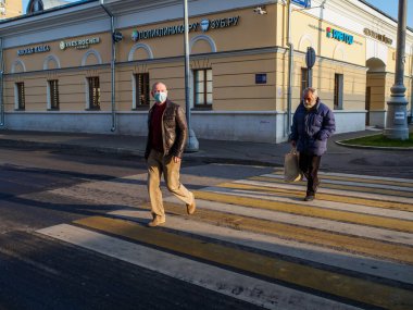 Moskova. - Rusya. 28 Ekim 2020. Yüz maskesi takan bir adam yaya geçidinde karşıdan karşıya geçiyor. Şehirde güneşli bir gün. Viral enfeksiyona karşı kişisel koruma kavramı.