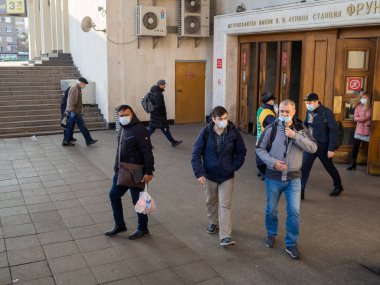 Moskova. - Rusya. 28 Ekim 2020. Maskeli yolcular Moskova metro istasyonundan eski ahşap kapılardan çıkıyorlar. Toplu taşımada tıbbi maske takmak zorunludur..