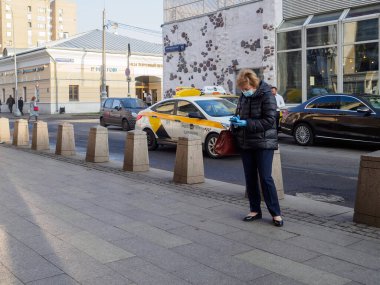 Moskova. - Rusya. 28 Ekim 2020. Koruyucu tıbbi maskeli ve lateks eldivenli bir kadın şehir caddesinde duruyor. Güneşli bir gün. Kirlenmeye karşı önlemler. Koronavirüsün ikinci dalgası..