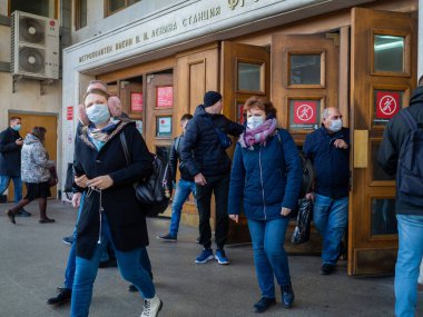 Moskova. - Rusya. 28 Ekim 2020. Maskeli yolcular Moskova metro istasyonundan eski ahşap kapılardan çıkıyorlar. Toplu taşımada tıbbi maske takmak zorunludur..