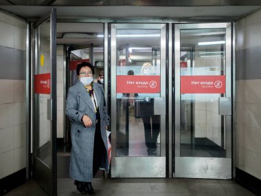 Moskova. - Rusya. 26 Ekim 2020. Yüz maskesi takan yolcular Moskova metro istasyonunu cam kapılardan terk ediyor. Toplu taşımada tıbbi maske takmak zorunludur..