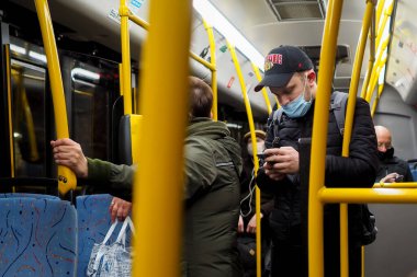 Moskova. - Rusya. 27 Ekim 2020. Otobüsteki genç bir adam akıllı telefon ekranına dikkatlice bakar. Yolcunun yüzünde koruyucu bir maske var. Koronavirüs salgınının ikinci dalgası..