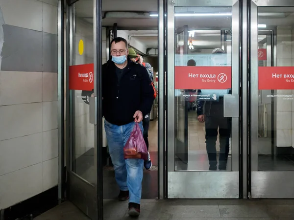 モスクワだ。ロシアだ。2020年10月26日フェイスマスクを着用した乗客は、ガラスドアを介してモスクワ地下鉄駅を離れる. — ストック写真