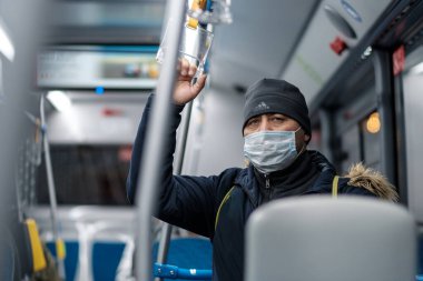 Şehir otobüsünde koruyucu bir maske takan bir adam..
