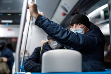 Şehir otobüsünde koruyucu bir maske takan bir adam..