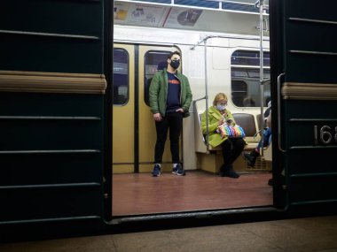 Metro vagonunda bir adam. Yolcunun yüzünde koruyucu bir tıbbi maske var.. 