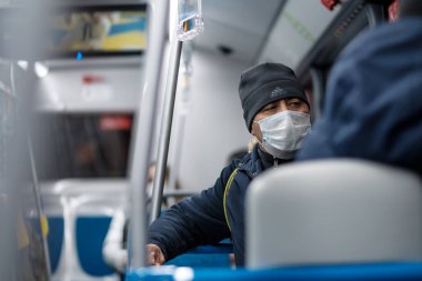 Şehir otobüsünde koruyucu bir maske takan bir adam..