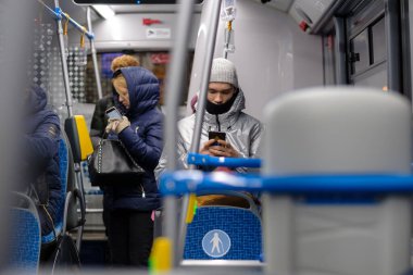 Otobüsteki genç bir adam akıllı telefon ekranına dikkatlice bakar..