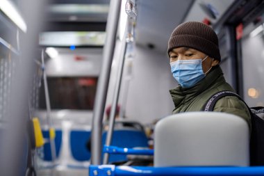 Şehir otobüsünde koruyucu bir maske takan bir adam..