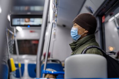 Şehir otobüsünde koruyucu bir maske takan bir adam..