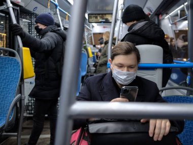Moskova. - Rusya. 1 Aralık 2020. Maskeli bir adam otobüste akıllı telefon kullanır. Toplu taşımacılıkta viral enfeksiyonlara karşı korunma.