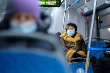 Moskova. - Rusya. 3 Aralık 2020. Yetişkin bir kadın toplu taşımada cerrahi koruyucu maske takıyor. Toplu taşımacılıkta viral enfeksiyona karşı önleyici tedbirler.