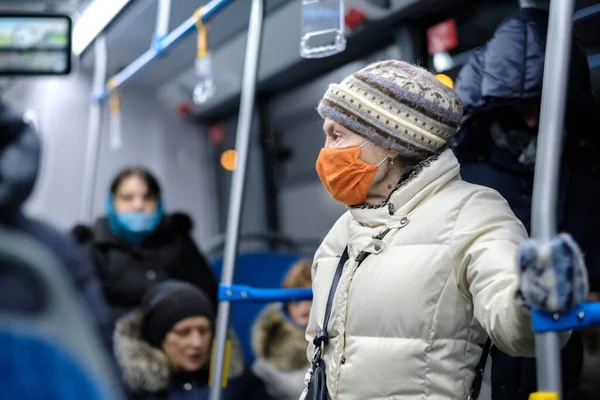 Пожилая женщина в хирургической защитной маске в общественном транспорте. — стоковое фото