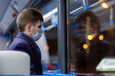 Şehir otobüsündeki bir adam viral enfeksiyonlara karşı koruyucu bir maske takıyor..
