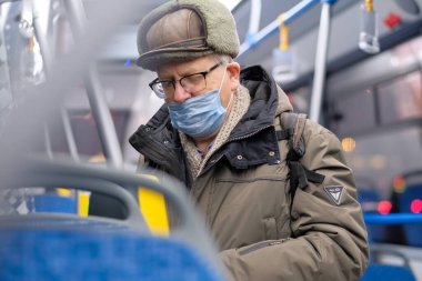 Şehir otobüsünde koruyucu bir maske takan bir adam..