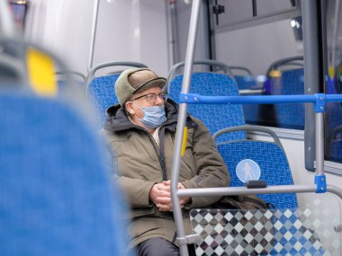 Şehir otobüsünde koruyucu bir maske takan bir adam..