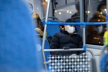 Şehir otobüsünde koruyucu bir maske takan bir adam..