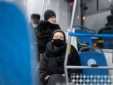 Toplu taşımada cerrahi koruyucu maske takan genç bir kadın.. 