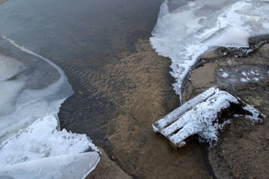Su buz kütleleri arasında akıyor. Bir kış gününde donmuş bir nehrin yüzeyi.
