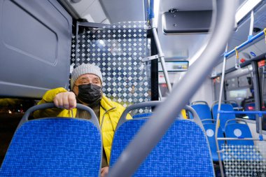 Şehir otobüsünde koruyucu bir maske takan bir adam..