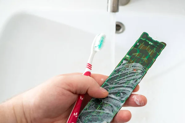 Cleaning the electronic board from the TV remote with a toothbrush and foam
