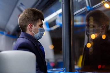 Şehir otobüsündeki bir adam viral enfeksiyonlara karşı koruyucu bir maske takıyor..