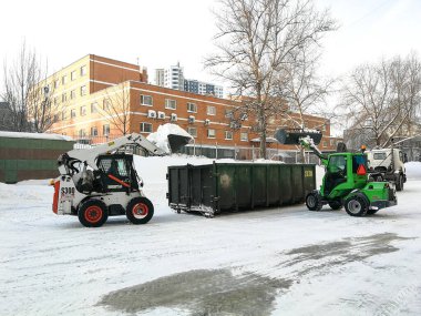  Küçük ön cephe yükleyicileri sokaktan kar temizler ve bir sığınağa yüklenir..