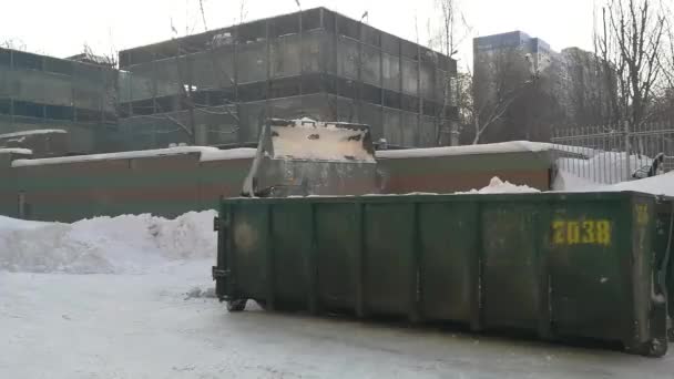 Pequenos carregadores frontais limpam a neve da rua e carregam em um bunker. — Vídeo de Stock