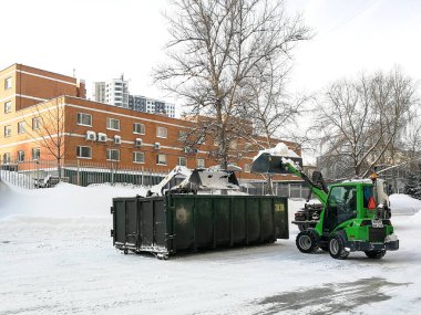  Küçük ön cephe yükleyicileri sokaktan kar temizler ve bir sığınağa yüklenir..