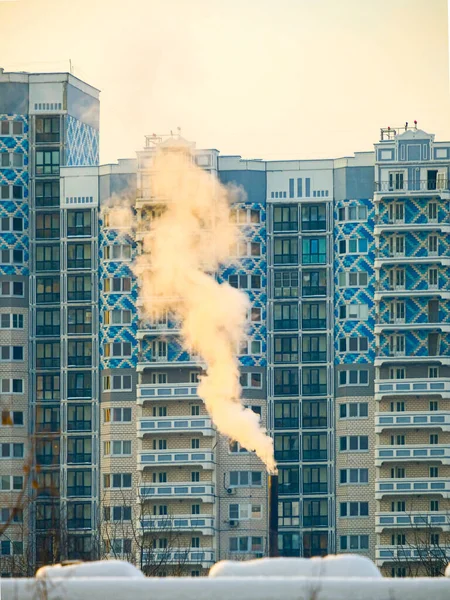 Smoke from the exhaust pipe against the background of a multi-storey building