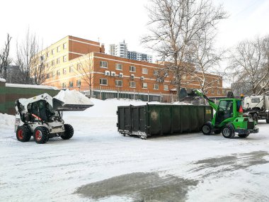  Küçük ön cephe yükleyicileri sokaktan kar temizler ve bir sığınağa yüklenir..