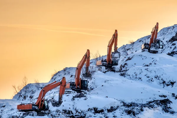 Siluetas de varias excavadoras trabajando en una enorme montaña en un basurero — Foto de Stock