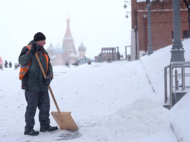 Kızıl Meydan 'da çalışan bir erkek işçi yoğun kar yağışı sonrası kar kürüyor..