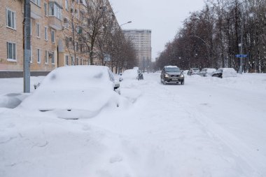 Yol boyunca park etmiş arabalar kalın bir kar tabakasıyla kaplıdır..