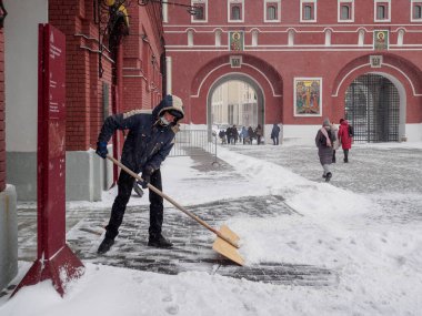 Bir adam kış günü tahta bir kürekle kaldırımdan karı kaldırır..