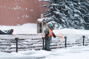 Bir kamu görevlisi Kremlin duvarının yakınındaki bir karakolda askerin yanında kar temizliyor..