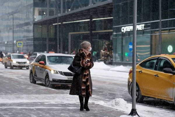 Eine Frau läuft im Winter die Straße hinunter, Schnee fällt. — Stockfoto