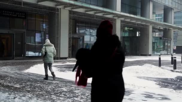 La gente camina a lo largo del edificio a través de una ventisca con fuertes nevadas. — Vídeo de stock