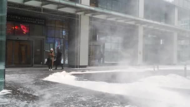 İnsanlar yoğun bir kar yağışı ile birlikte bina boyunca yürürler.. — Stok video