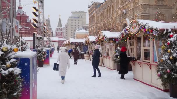 モスクワだ ロシアだ 2021年2月12日 いくつかの観光客は雪の中で冬の日に赤の広場で新年のフェアを歩く モスクワのクレムリン近くのGumスケートリンク — ストック動画