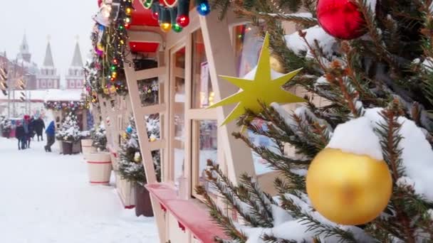 莫斯科 俄罗斯 2021年2月12日 一个闪亮的黄色圣诞球在白雪覆盖的树上 背景在莫斯科克里姆林宫 溜冰场和莫斯科红场的圣诞市场上 — 图库视频影像