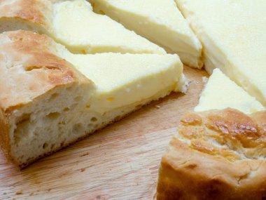 Üçgen dilimli ekşi turtaya yakın plan - ulusal bir Tatar yemeği. Büyük bir ev yapımı peynirli kek, kızarmış kenarları ve ahşap bir masada yumuşak bir dolgu..