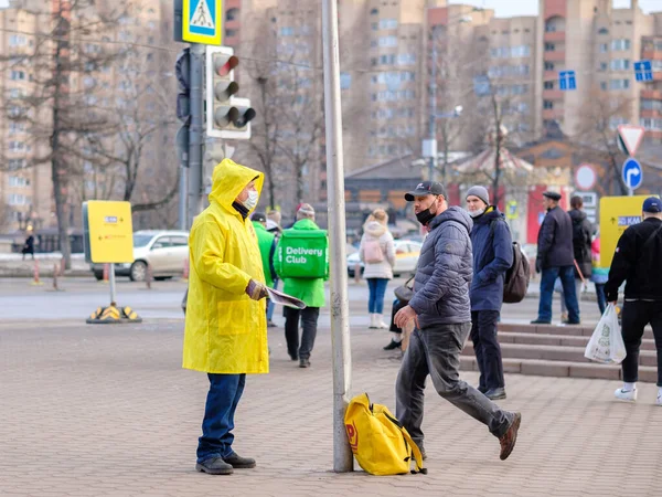 Egy sárga esőkabátos férfi politikai újságokat osztogat az embereknek.. — Stock Fotó