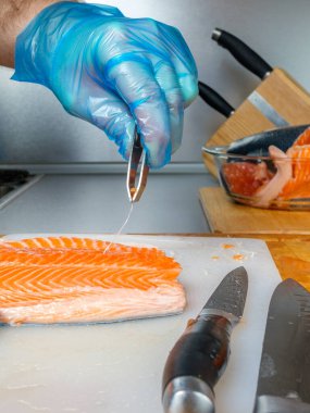 Şef somon filetosundaki kemikleri çıkarmak için özel balık cımbızı kullanıyor..